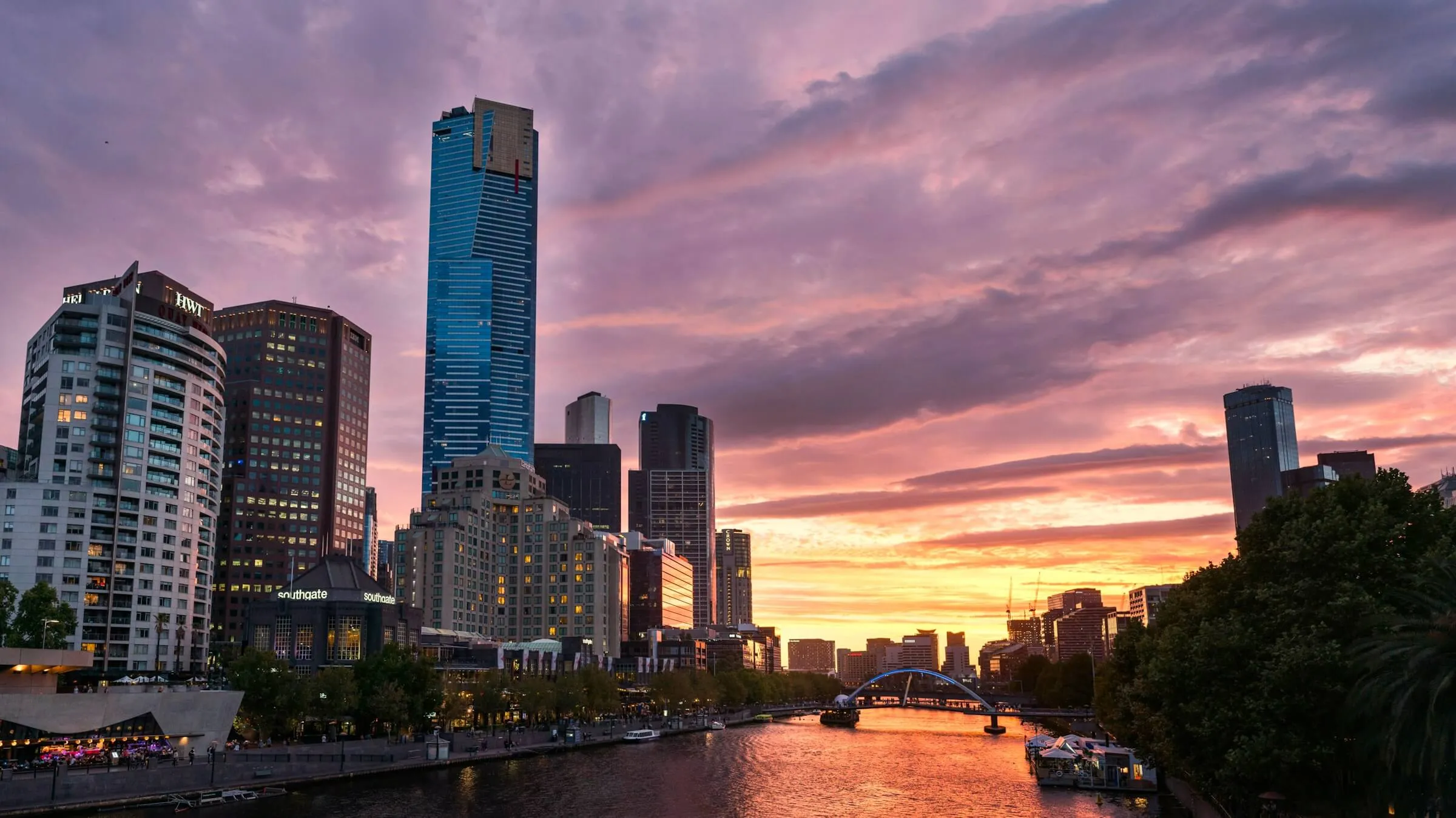 Eureka Tower rising over Southbank and the Yarra River against a pink and orange sunset sky